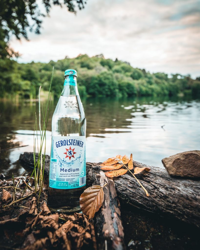 Eine Flasche Gerolsteiner Medium mit dem Dauner Maar im Hintergrund. 