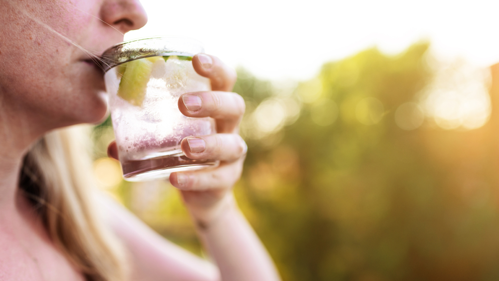 Frau trinkt hydrogencarbonatreiches Mineralwasser aus Glas.