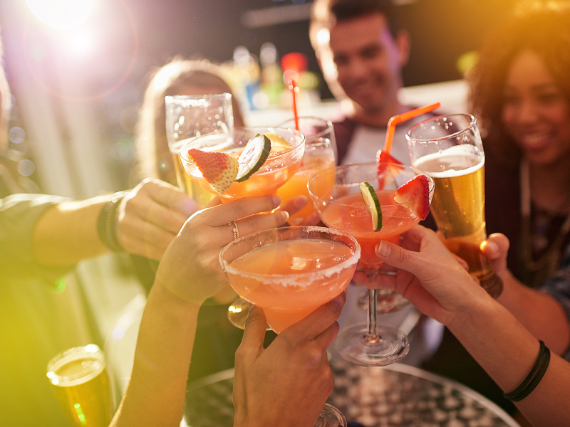 Eine Gruppe von Personen prostet sich mit verschiedenen alkoholischen Getränken zu.