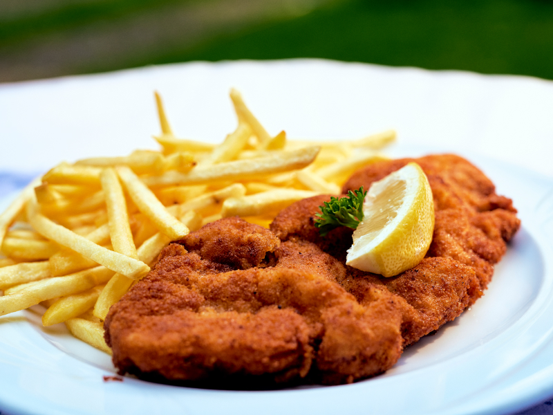 Schnitzel mit Pommes als Beilage auf einem weißen Teller.