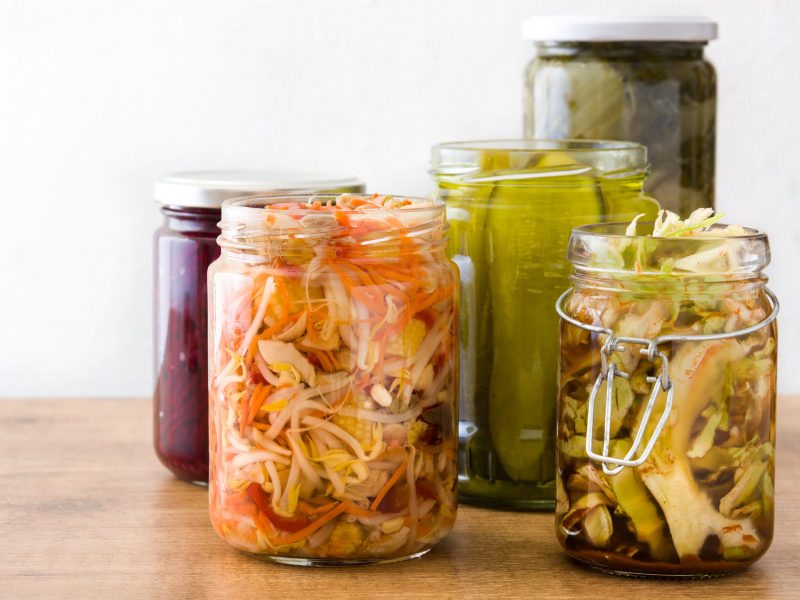 Fermentiertes Gemüse in Einmachgläsern auf einem Holztisch.