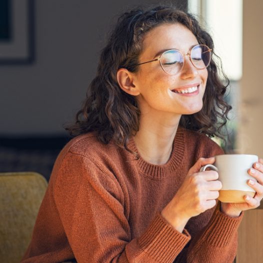 Glückliche Frau trinkt eine Tasse Kaffee.