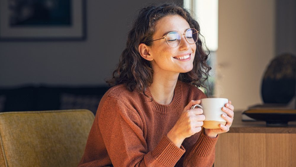 Glückliche Frau trinkt eine Tasse Kaffee.