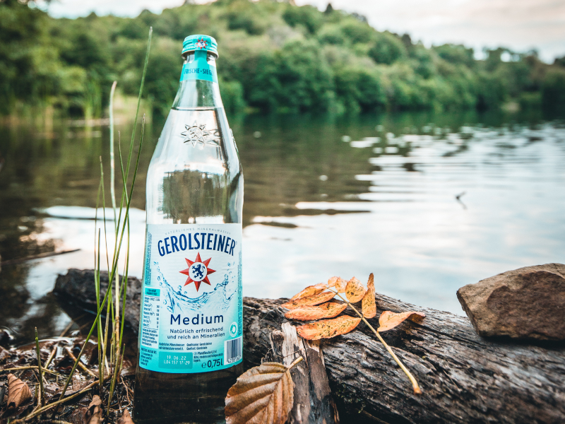 Eine Flasche Gerolsteiner Medium steht am Ufer eines Dauner Maars.