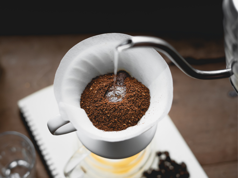 Kaffeepulver in einem Filter wird mit heißem Wasser übergossen.
