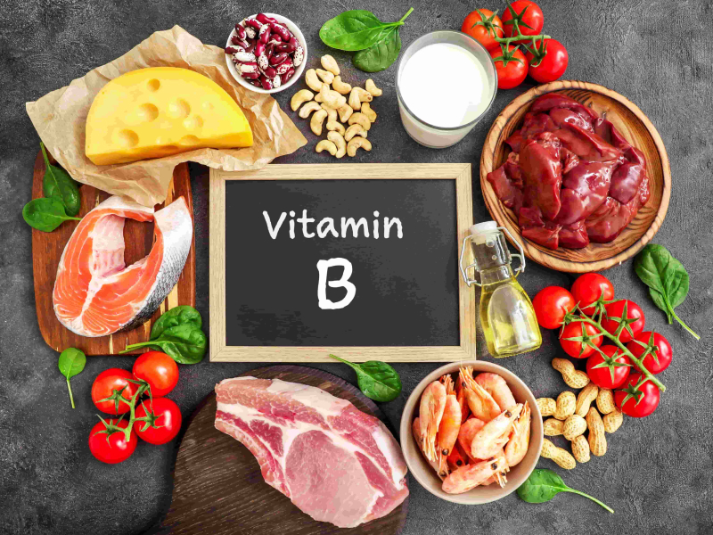 Lebensmittelquellen für Vitamin B. Darunter Käse, Nüsse, rotes Fleisch, Tomaten und Milch.