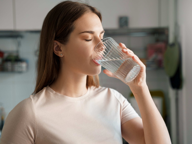 Frau trinkt Wasser aus einem Glas.