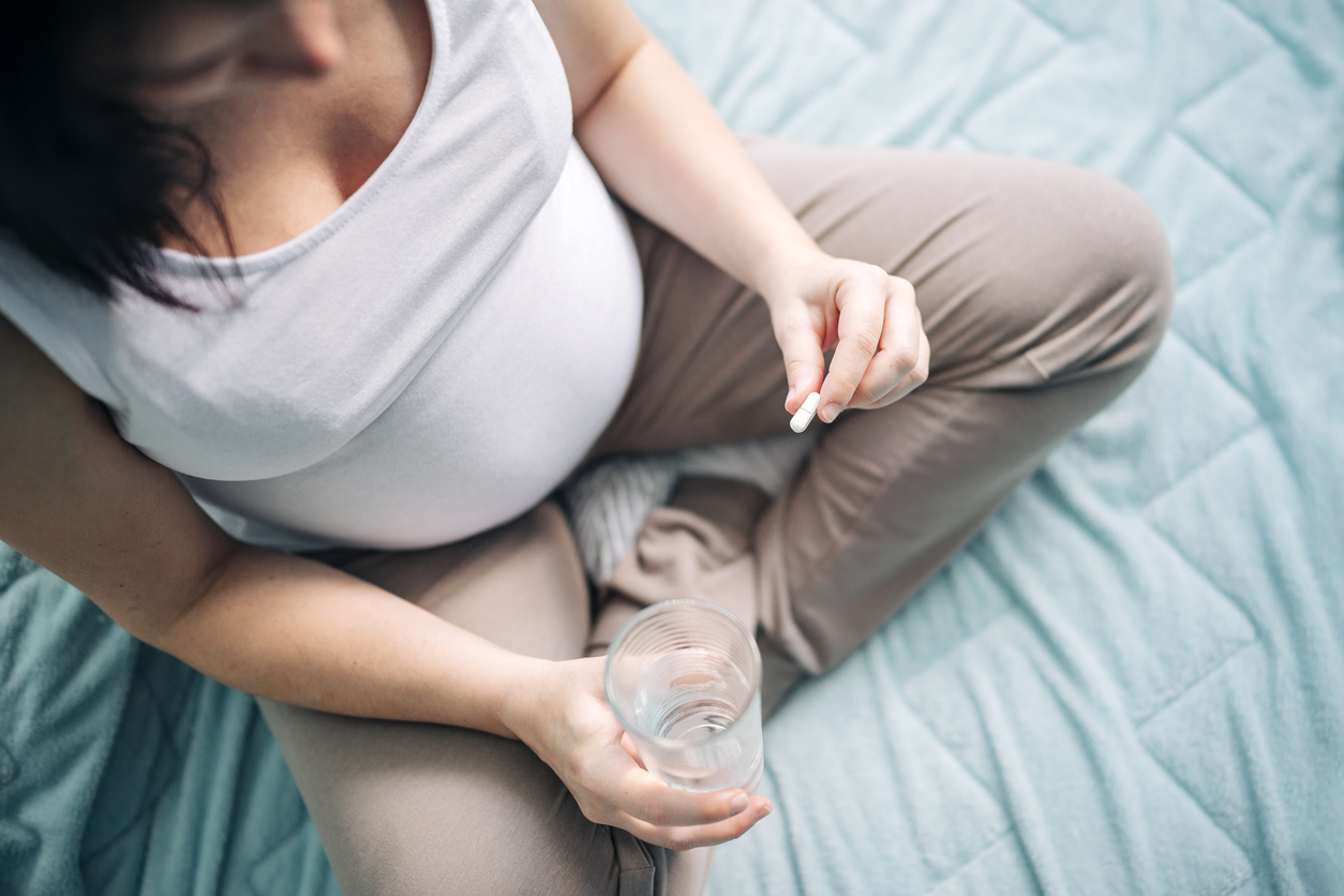 Frau nimmt eine Tabeltte mit einem Glas Wasser ein.