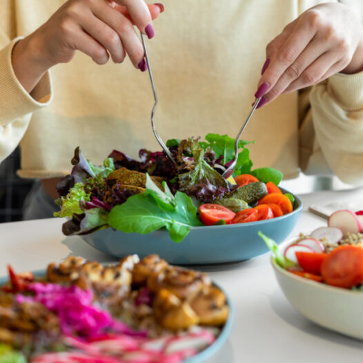 Frau isst einen frischen, bunten Salat mit grünem Gemüse, Tomaten und Falafel – eisenreiche Lebensmittel für eine gesunde Ernährung