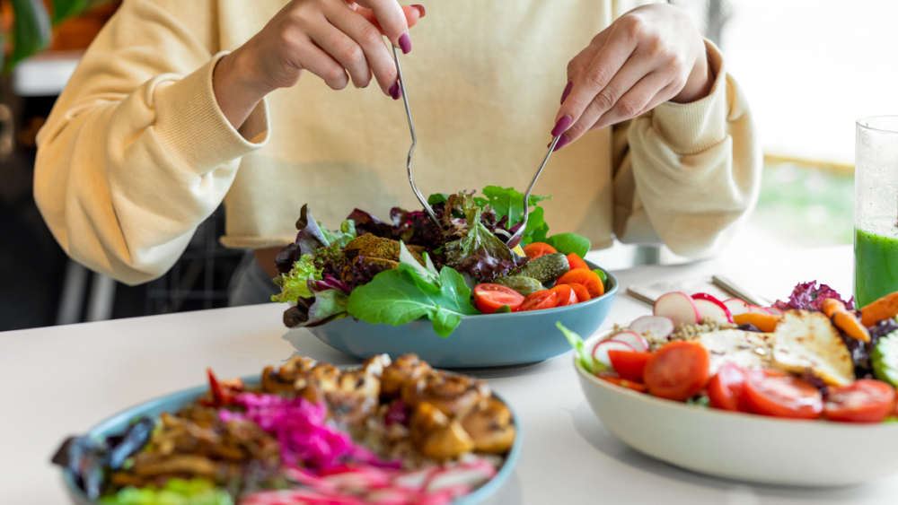 Frau isst einen frischen, bunten Salat mit grünem Gemüse, Tomaten und Falafel – eisenreiche Lebensmittel für eine gesunde Ernährung