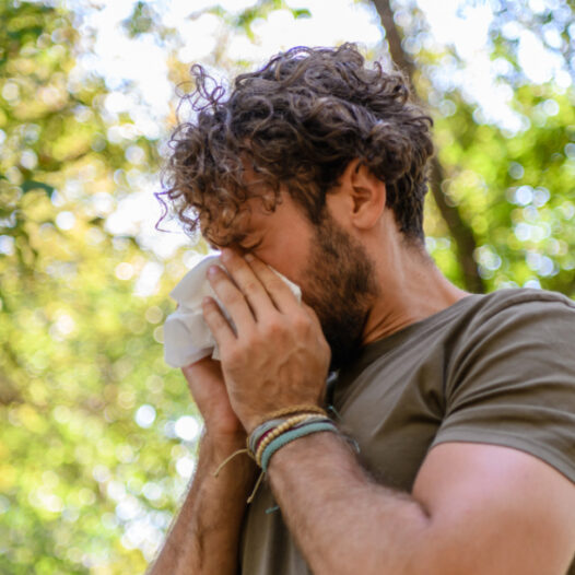 Mann mit Heuschupfen niest in ein Taschentuch